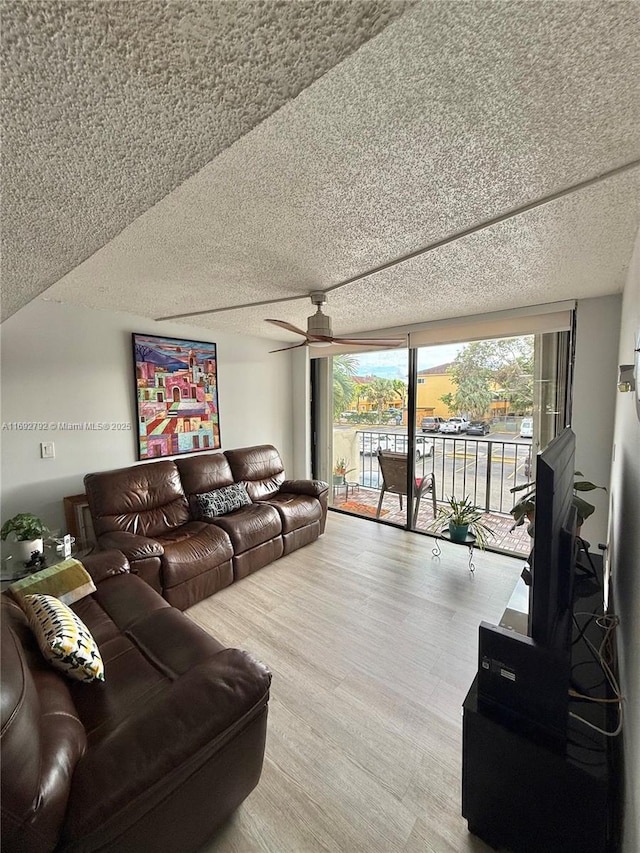 living room with hardwood / wood-style flooring, ceiling fan, and a textured ceiling