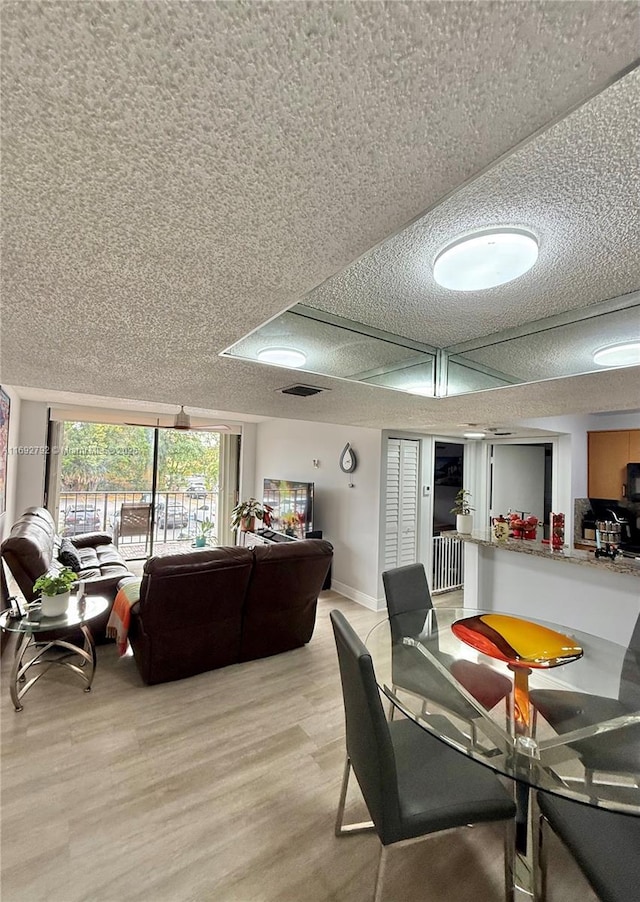 dining room featuring a textured ceiling and light wood-type flooring