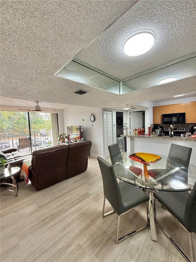 dining room with light hardwood / wood-style floors and a textured ceiling