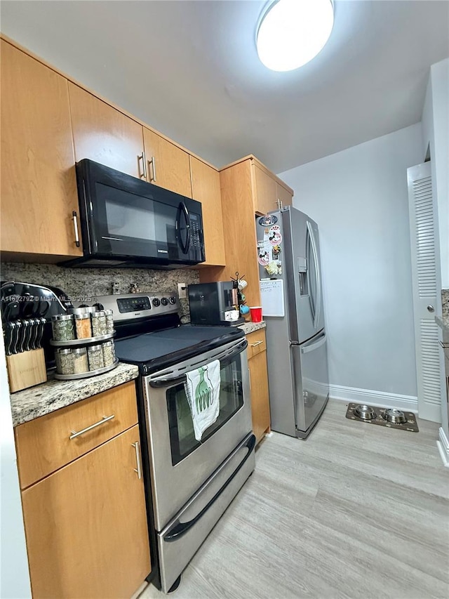 kitchen featuring light stone countertops, appliances with stainless steel finishes, and light hardwood / wood-style floors