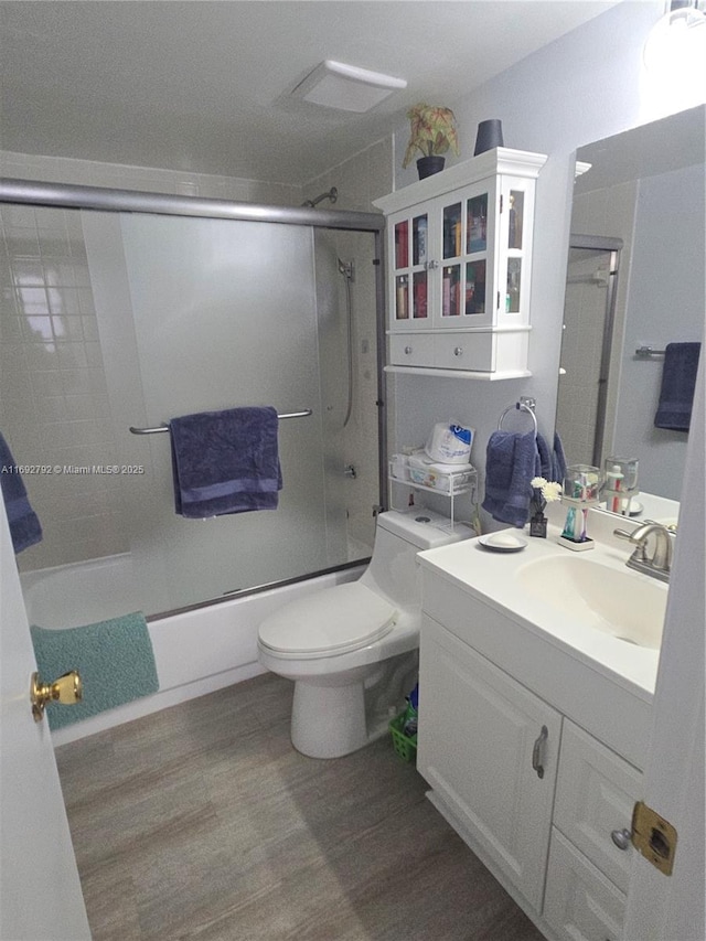 full bathroom with enclosed tub / shower combo, wood-type flooring, toilet, and vanity