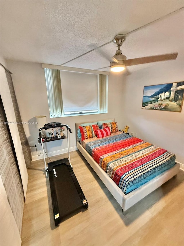 bedroom with hardwood / wood-style flooring, a textured ceiling, and ceiling fan