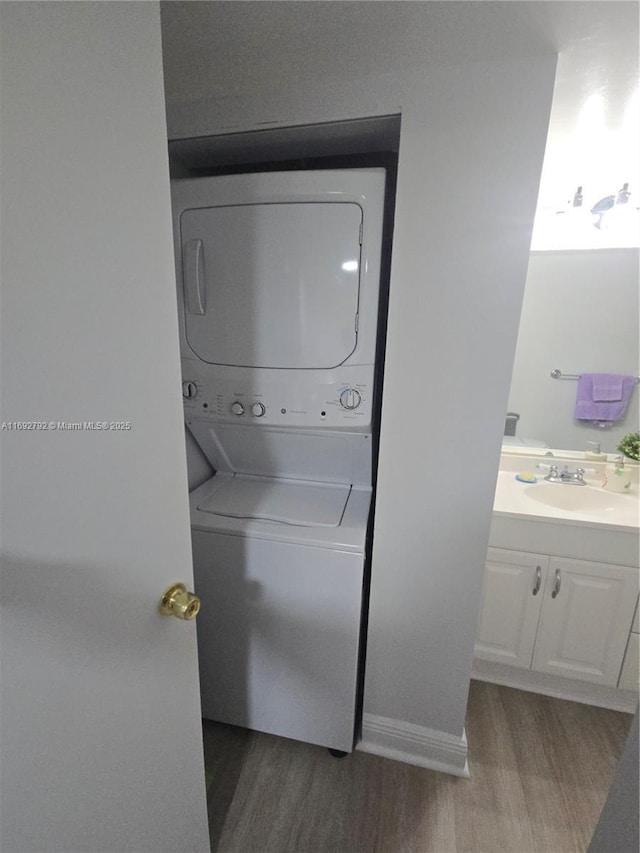 laundry room featuring stacked washer / dryer, sink, and hardwood / wood-style floors