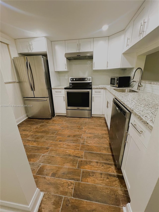 kitchen with sink, dark hardwood / wood-style floors, appliances with stainless steel finishes, light stone counters, and white cabinetry