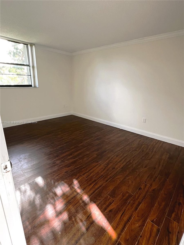 empty room featuring dark hardwood / wood-style flooring and crown molding