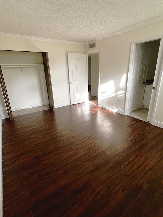 unfurnished bedroom featuring ornamental molding, a textured ceiling, a closet, and dark wood-type flooring