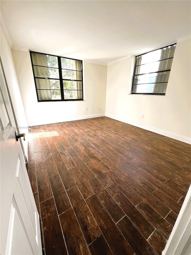 empty room featuring ornamental molding and dark wood-type flooring