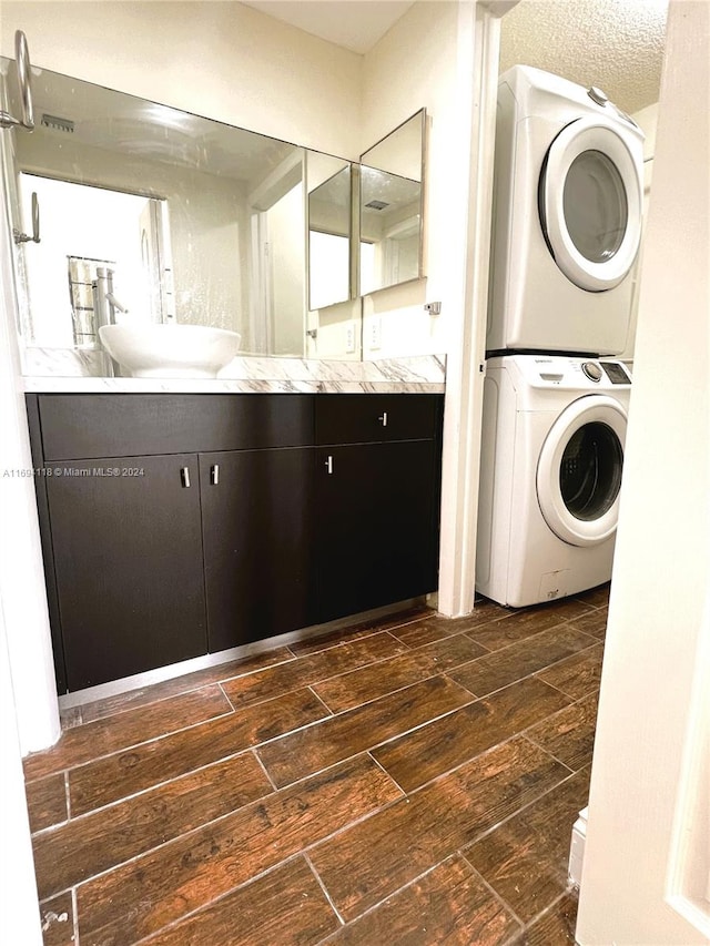 washroom featuring stacked washer / dryer, sink, and a textured ceiling