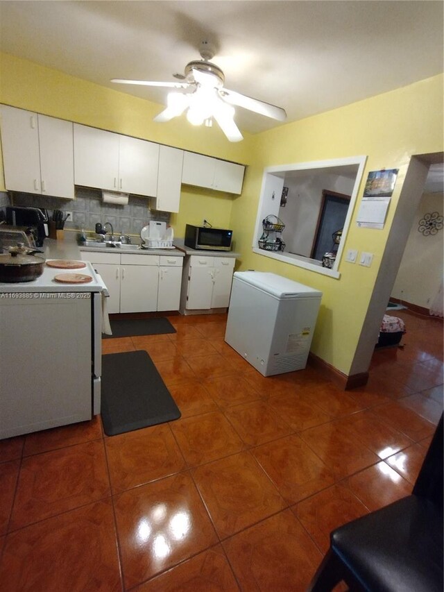 kitchen featuring ceiling fan, fridge, decorative backsplash, white cabinets, and dark tile patterned flooring