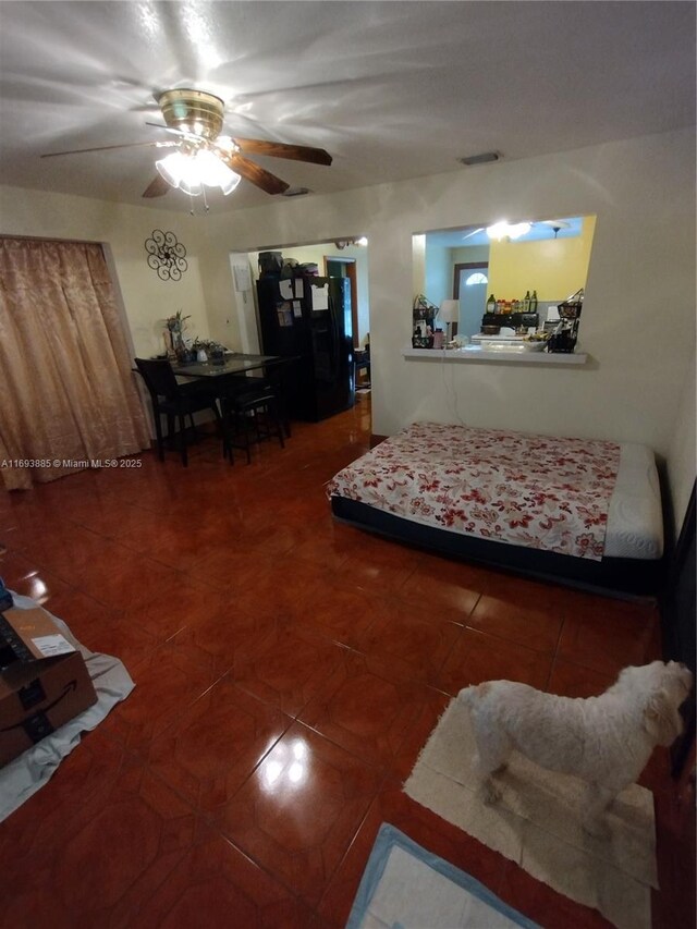 tiled bedroom featuring ceiling fan and black refrigerator