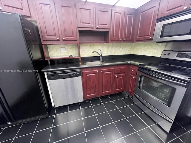 kitchen with backsplash, sink, dark tile patterned floors, and stainless steel appliances