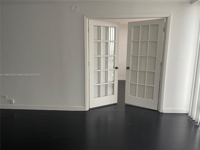 spare room featuring dark wood finished floors and baseboards