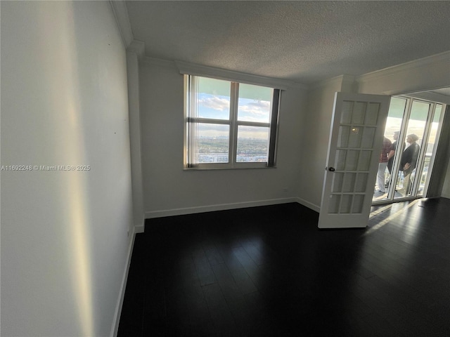 unfurnished room featuring ornamental molding, a textured ceiling, baseboards, and wood finished floors