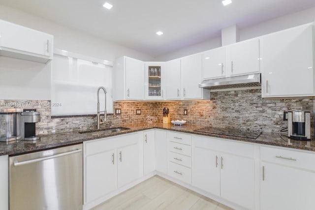 kitchen featuring a sink, stainless steel dishwasher, black electric stovetop, under cabinet range hood, and dark stone counters