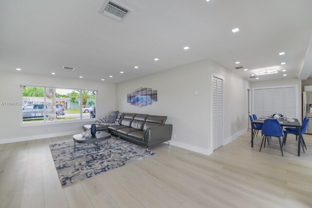 living room featuring baseboards, visible vents, light wood-style floors, and recessed lighting
