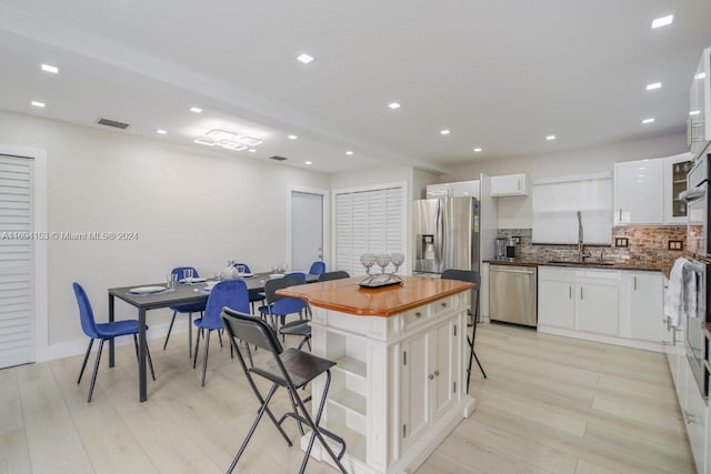 kitchen featuring decorative backsplash, white cabinets, a breakfast bar, appliances with stainless steel finishes, and a sink