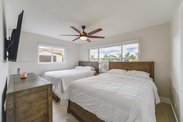 bedroom featuring baseboards, light wood-style floors, and a ceiling fan