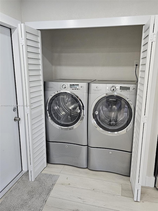 laundry room with light wood-style floors, laundry area, and separate washer and dryer
