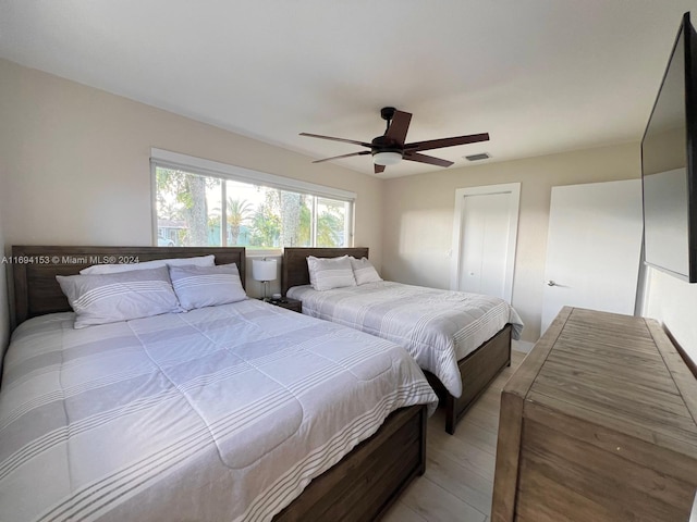 bedroom featuring light wood-type flooring, visible vents, and a ceiling fan
