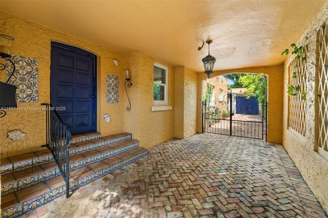 view of exterior entry featuring a gate and stucco siding