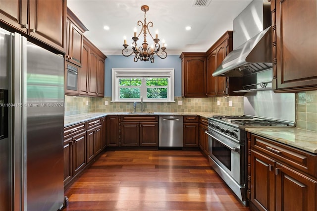 kitchen with appliances with stainless steel finishes, light stone counters, wall chimney exhaust hood, dark wood-type flooring, and pendant lighting