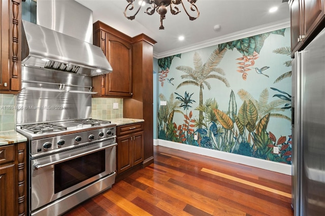 kitchen featuring light stone countertops, stainless steel appliances, wall chimney range hood, dark hardwood / wood-style flooring, and ornamental molding