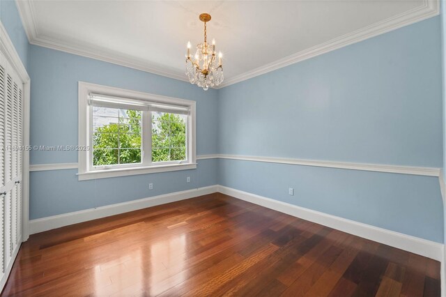 unfurnished room with hardwood / wood-style flooring, crown molding, and a notable chandelier