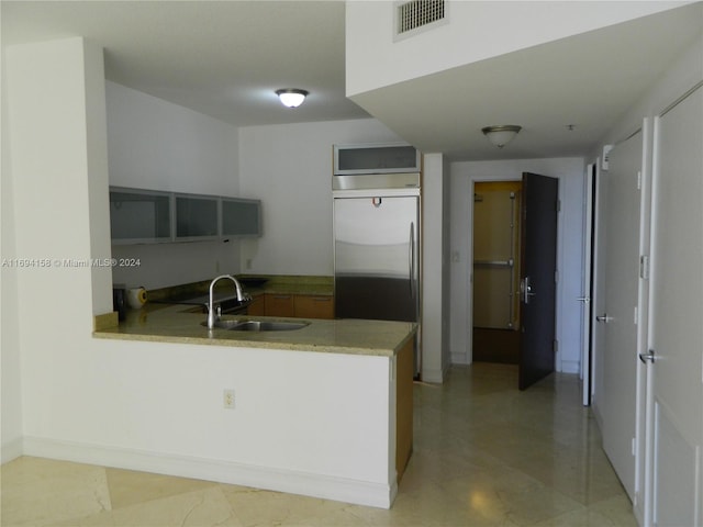 kitchen featuring stainless steel built in refrigerator, kitchen peninsula, and sink