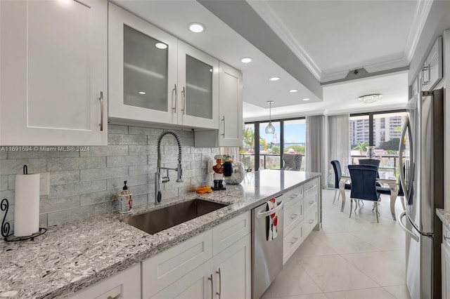 kitchen with white cabinets, sink, ornamental molding, appliances with stainless steel finishes, and decorative light fixtures