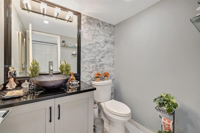 bathroom featuring vanity, toilet, and tile walls