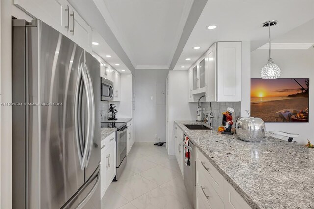 kitchen featuring white cabinets, decorative light fixtures, stainless steel appliances, and ornamental molding