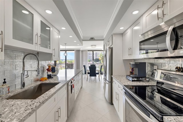 kitchen featuring backsplash, light stone counters, stainless steel appliances, sink, and white cabinetry