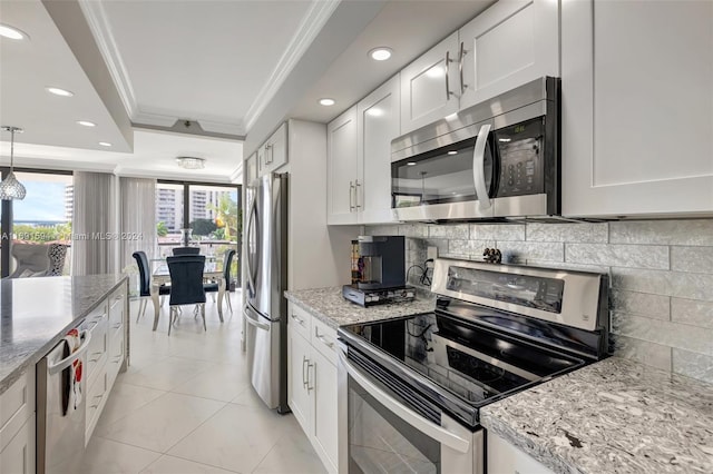 kitchen with white cabinetry, crown molding, decorative light fixtures, a tray ceiling, and appliances with stainless steel finishes