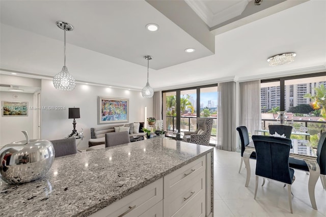 kitchen with light stone counters, crown molding, light tile patterned floors, decorative light fixtures, and white cabinetry