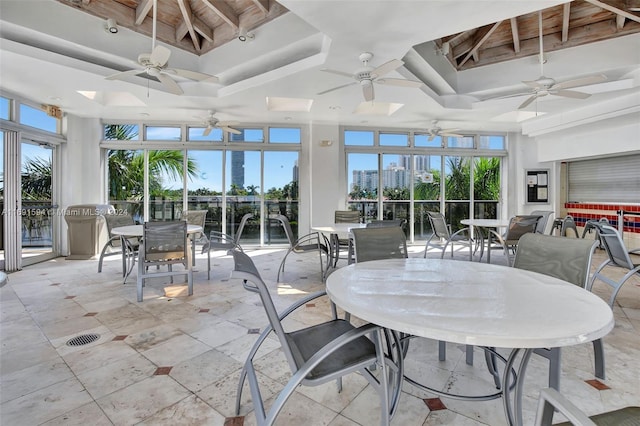 sunroom / solarium featuring a raised ceiling, ceiling fan, and a healthy amount of sunlight