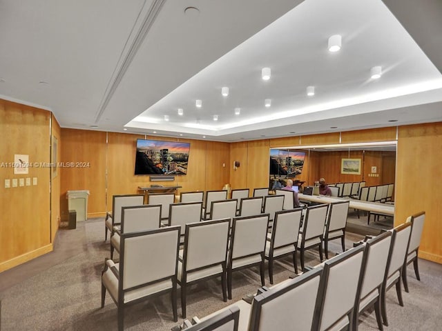 home theater room featuring a tray ceiling and wooden walls