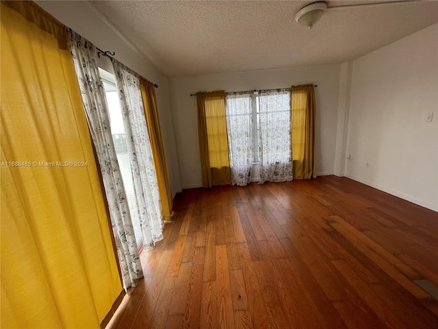 unfurnished room featuring a textured ceiling, dark wood-type flooring, and a wealth of natural light