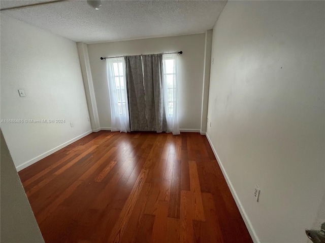 unfurnished room featuring a textured ceiling and dark hardwood / wood-style flooring