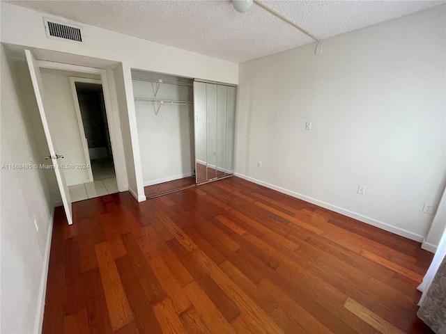 unfurnished bedroom featuring a closet, dark wood-type flooring, and a textured ceiling