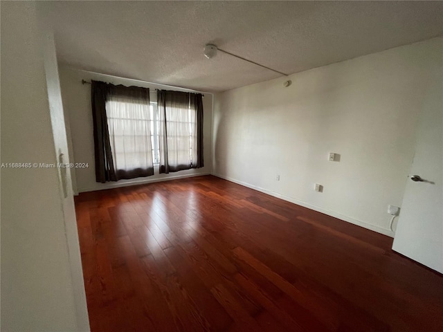 unfurnished room featuring dark hardwood / wood-style flooring and a textured ceiling