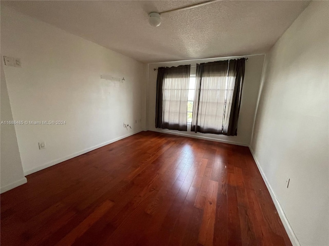 empty room with dark hardwood / wood-style floors and a textured ceiling