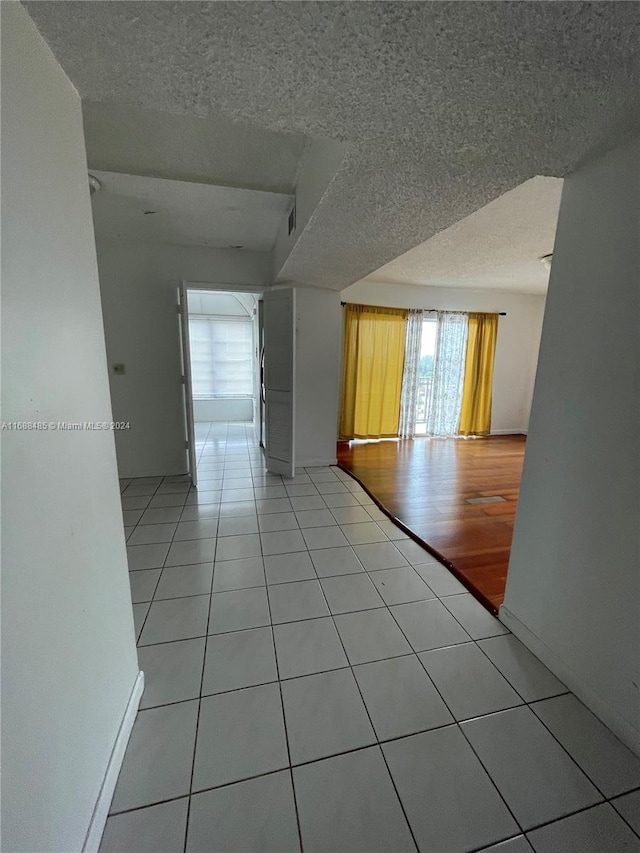 unfurnished room with a textured ceiling and light wood-type flooring