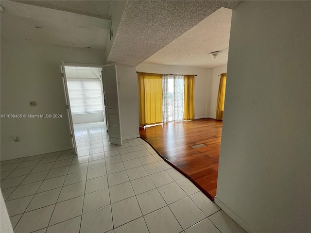 empty room with a textured ceiling and light hardwood / wood-style flooring