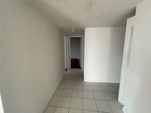 hall with light tile patterned floors and a textured ceiling