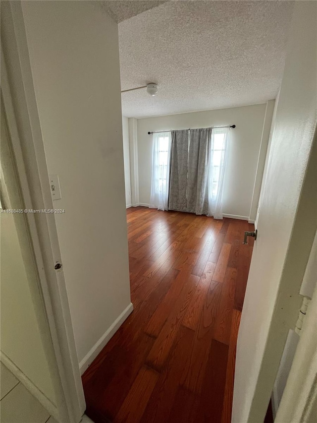 hall with hardwood / wood-style floors and a textured ceiling