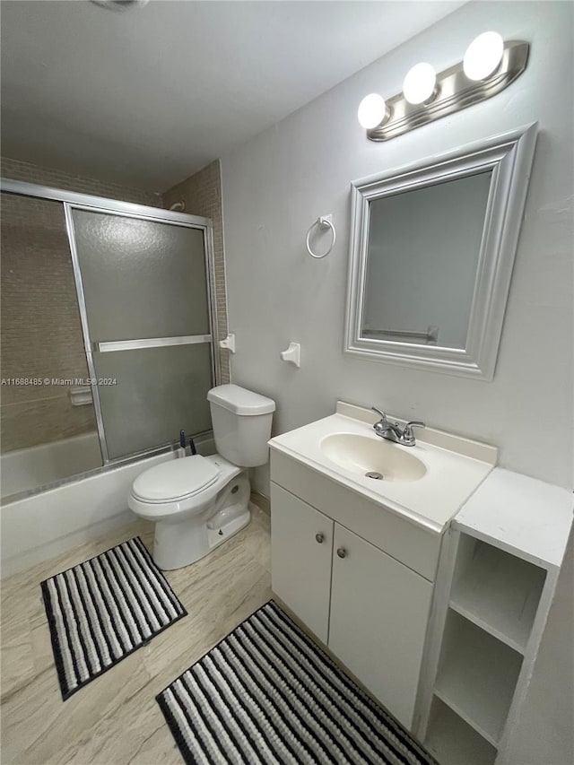 full bathroom with wood-type flooring, vanity, toilet, and enclosed tub / shower combo