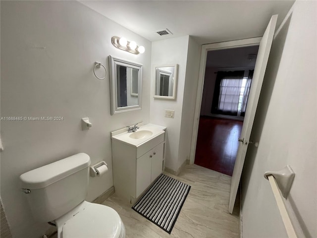 bathroom featuring toilet, vanity, and hardwood / wood-style flooring