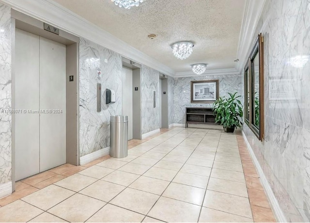 hall with an inviting chandelier, elevator, light tile patterned floors, ornamental molding, and a textured ceiling