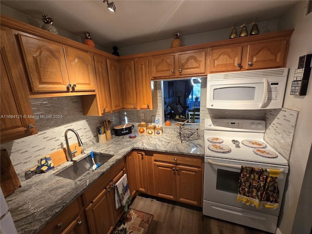 kitchen with light stone countertops, dark hardwood / wood-style flooring, white appliances, and sink