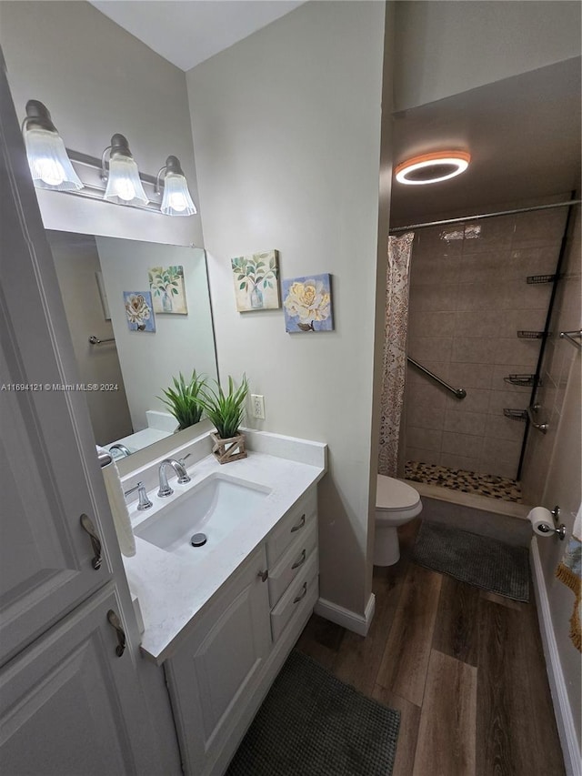 bathroom with toilet, hardwood / wood-style floors, vanity, and walk in shower